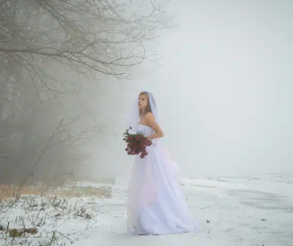 Panna młoda w białej sukni ślubnej z długim welonem, zimowa atrakcja weselna